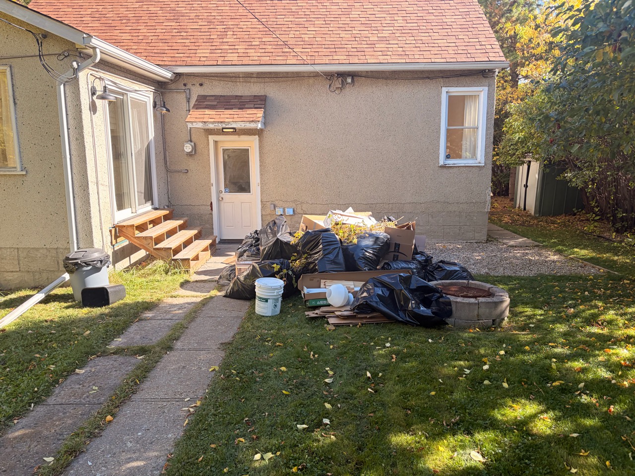 Before junk removal: bags, cardboard and loose items piled beside the back steps
